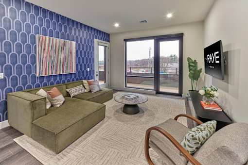 A living room with a blue patterned wall and a flat screen TV mounted on the wall.