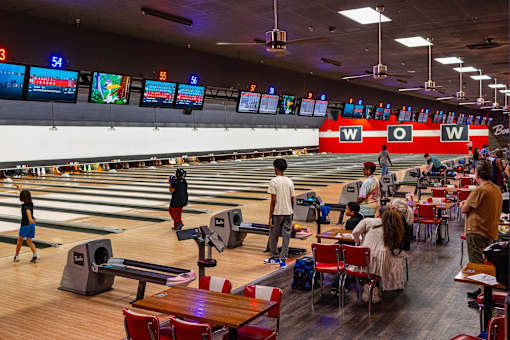 A bowling alley with people playing and a scoreboard showing 54.