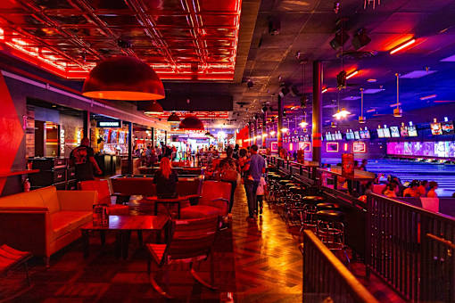 A bar with people sitting and standing at the bar.