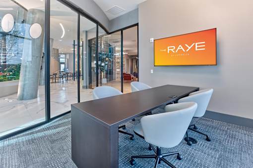 A conference room with a long table and chairs with a sign that says RAYE.
