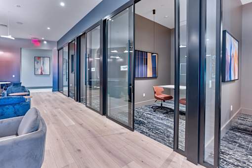 A modern office space with glass walls and a blue sofa.