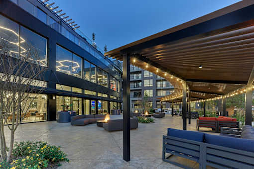 A modern building with a glass facade and a covered outdoor seating area.