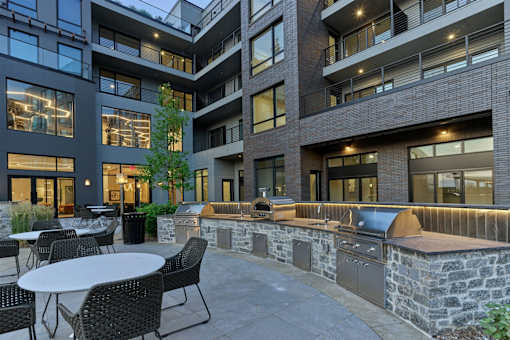 A patio with a table and chairs is surrounded by a stone wall and a brick building.