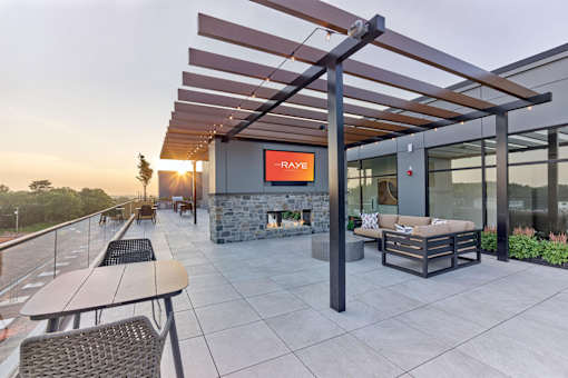 A patio with a fireplace and seating area under a pergola.