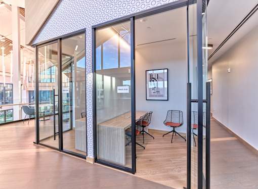 A modern office space with glass walls and wooden floors.