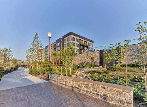 A modern building with a stone wall and a wooden walkway in front.