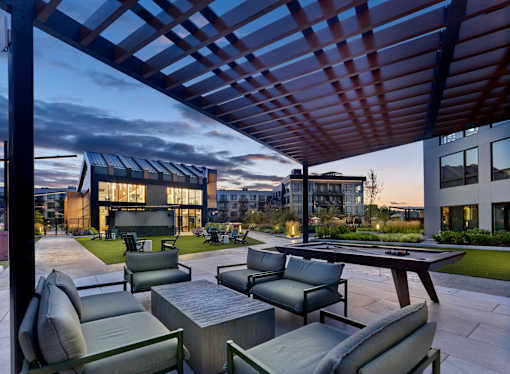 A modern outdoor seating area with a pool table and comfortable chairs.