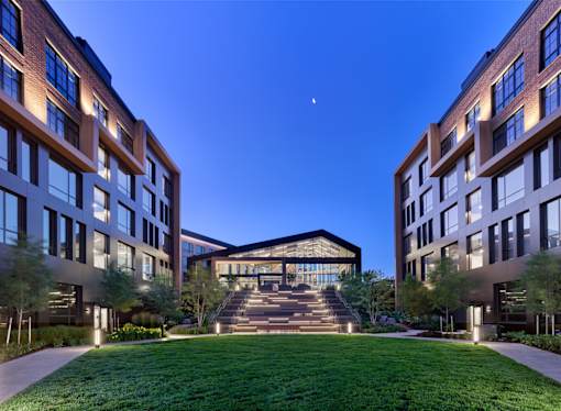 A modern building with a large glass entrance and a green lawn in front.