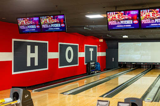 A bowling alley with a red wall that has the letters H, O, T on it.