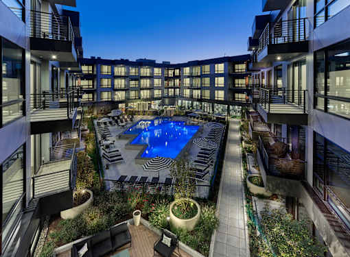 A swimming pool surrounded by balconies and potted plants.