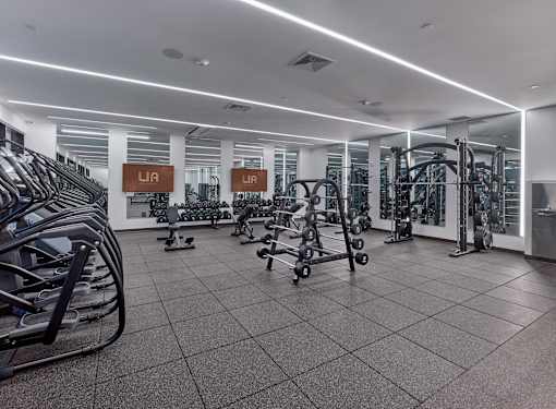 A gym with a variety of equipment including treadmills, weights, and exercise machines.