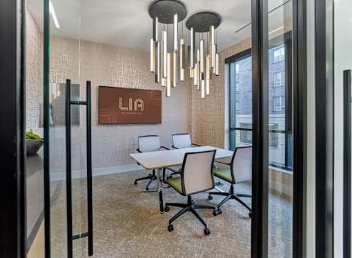 A conference room with a white table and chairs, a brown L&N logo on the wall, and a chandelier hanging from the ceiling.