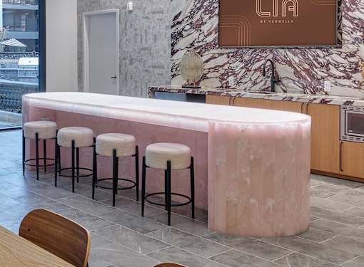 A bar with a pink marble counter and stools.