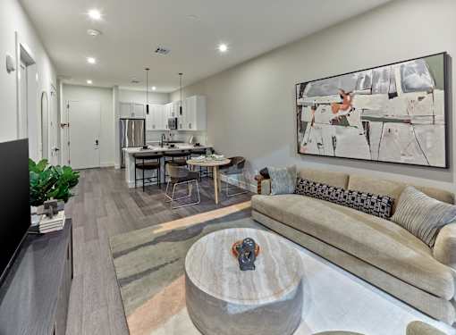 A modern living room with a grey couch and a large abstract painting on the wall.