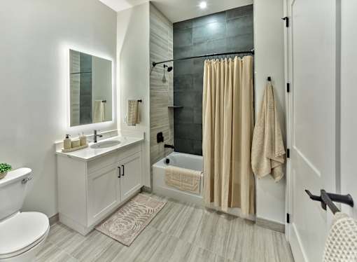A bathroom with a white toilet, sink, and shower area.