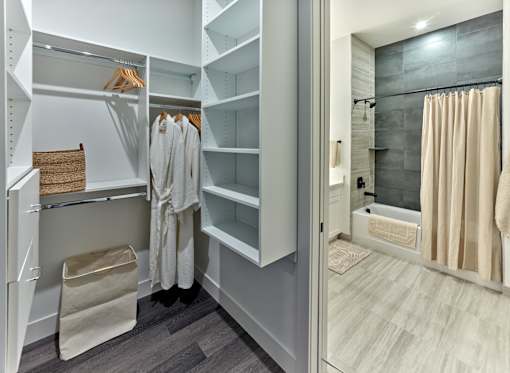 A bathroom with a walk-in shower and a large closet with white shelves.