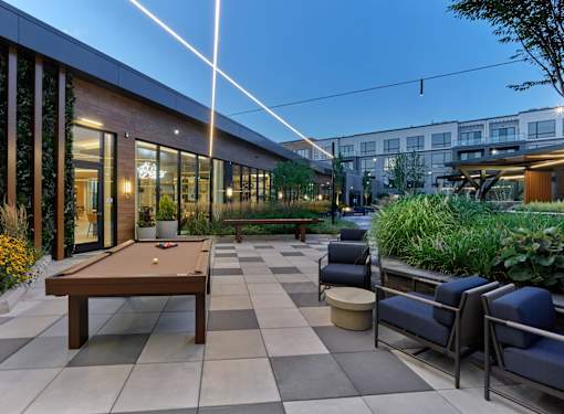 A pool table is surrounded by chairs in a patio area.