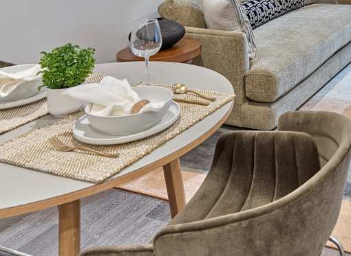 A dining table with a glass of water, a napkin, and a plant on it.