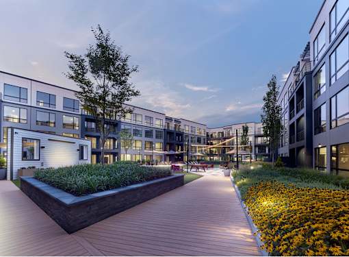 A modern building complex with a wooden walkway and flower beds.