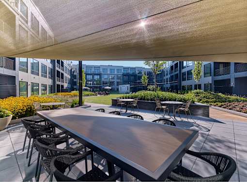 A large wooden table is surrounded by chairs on a patio.