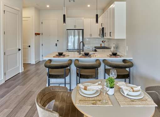 A modern kitchen with a dining table set for two.