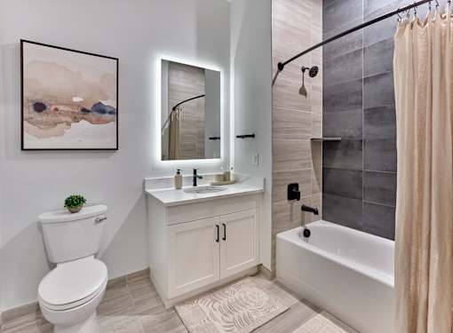 A bathroom with a white toilet, a sink with a mirror, and a bathtub with a shower curtain.