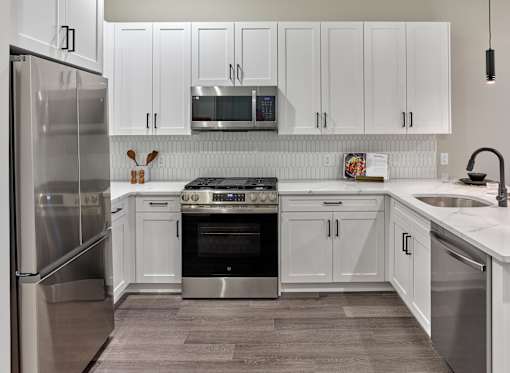 A modern kitchen with white cabinets and stainless steel appliances.