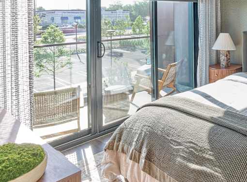 A bedroom with a large window overlooking a parking lot.