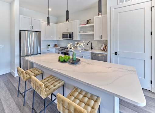 A kitchen with a marble countertop and bar stools.