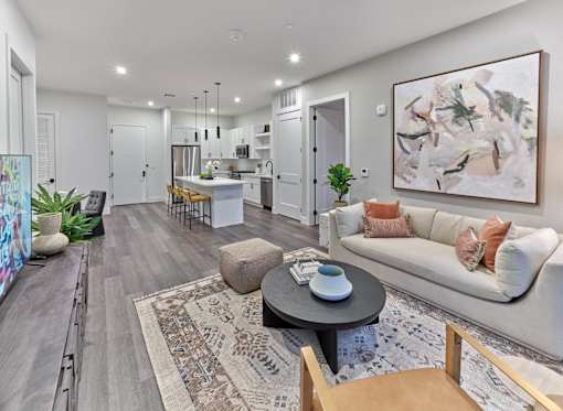 A modern living room with a white couch and a large abstract painting on the wall.