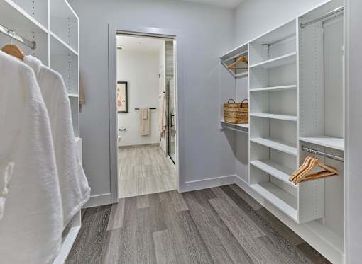 A white closet with a mirror and a brown basket on the shelf.