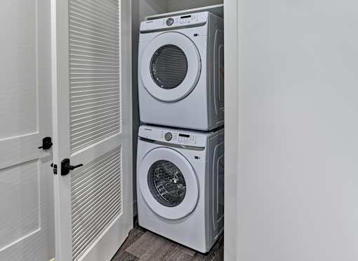 A white washing machine and dryer stacked on top of each other in a laundry room.