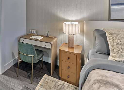 A bedroom with a bed, desk, chair, and nightstand.