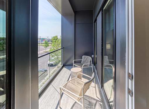 A balcony with two chairs and a table is shown.