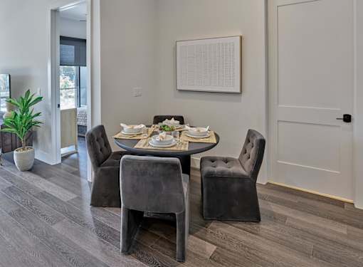 A dining table with four chairs and a potted plant.