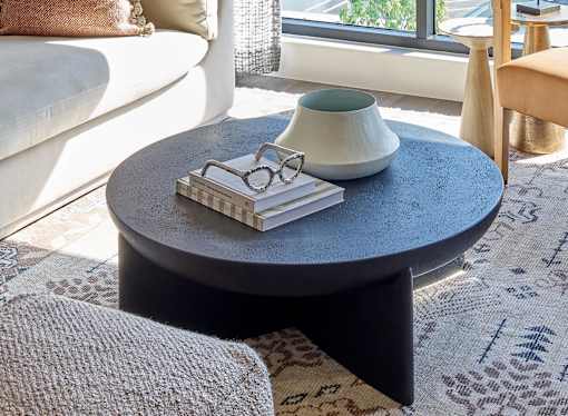 A round table with a vase, glasses, and books on it.