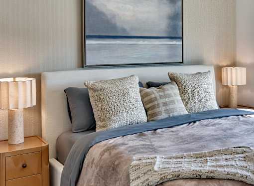 A bedroom with a large bed and a painting of a beach scene above it.