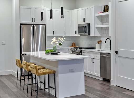 A modern kitchen with a white island and bar stools.