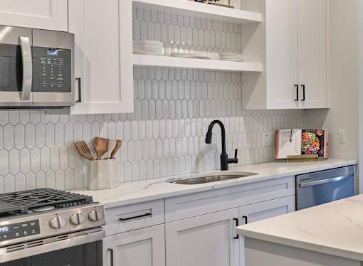 A modern kitchen with white cabinets and a silver stove top.