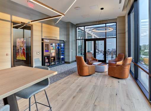 A modern office space with a wooden floor, a long table, and a view of the city.