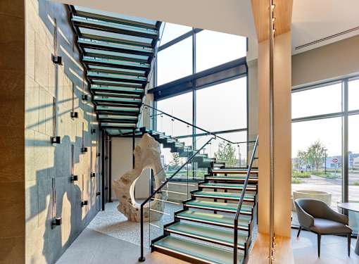 A staircase with a glass railing and a stone pillar.