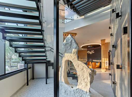 A large stone sculpture is in the foreground of a modern interior space.