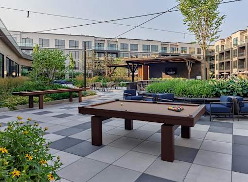A pool table is surrounded by chairs in a courtyard.