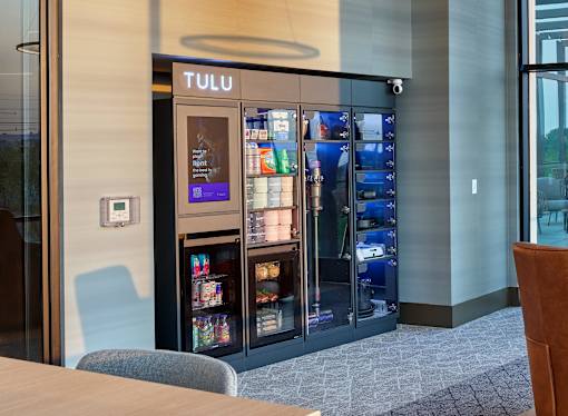A Tulu vending machine is in the middle of a room.