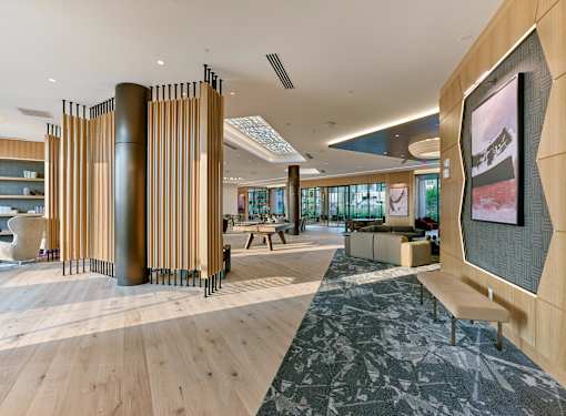 A modern office lobby with a wooden floor and a large screen on the right side.