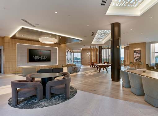 A modern living room with a round table and chairs, a flat screen TV, and a large window.