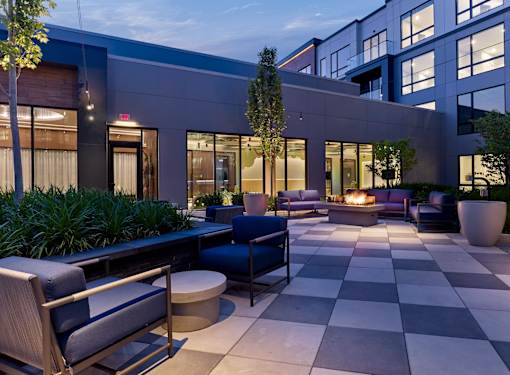 A modern outdoor seating area with a fire pit and comfortable seating.