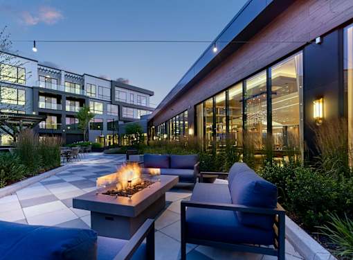 A modern outdoor seating area with a fire pit and couches.