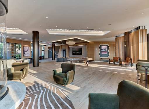 A large, modern living room with a variety of seating options and a flat-screen TV.