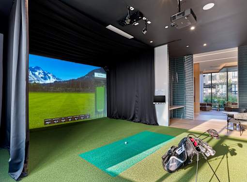 A golf simulator room with a screen showing a golf course.